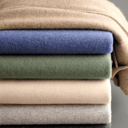 Stack of folded Monaco Hoodie in various colours, showcasing ultra-soft merino wool fabric, ideal for men's winter wear and layering.